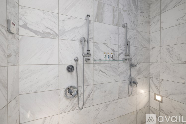 A bathroom with a marble tile wall and a shower with a glass door.