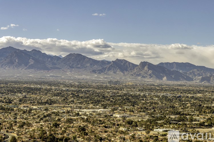 A landscape with mountains in the background and a cloudy sky above.
