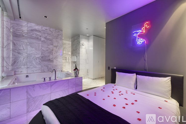 A modern bedroom with a large bed and a neon sign on the wall.