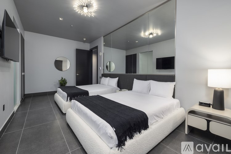 A modern bedroom with two beds and a television.