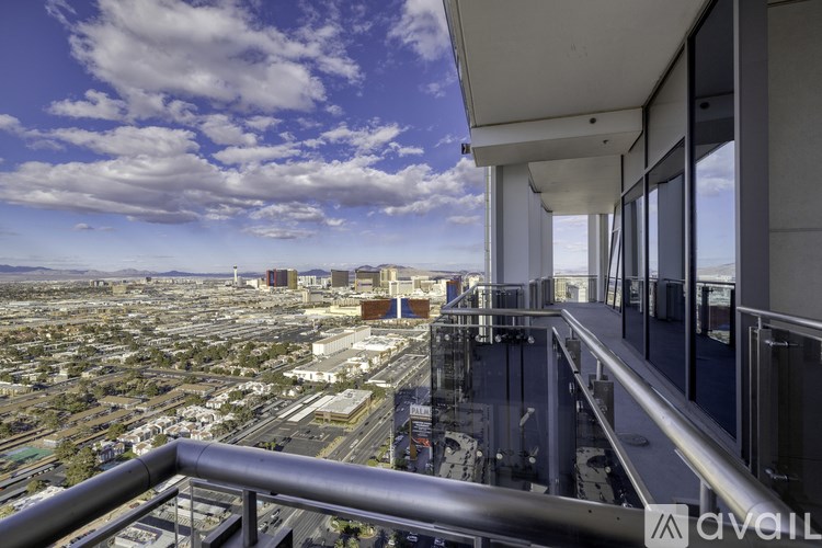 A balcony overlooks a cityscape with a clear blue sky above.