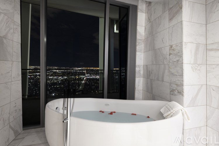 A white bathtub with a view of the city at night.
