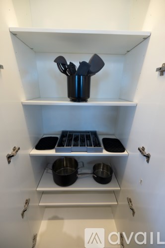A kitchen cabinet with a pot and a pan on the shelf.