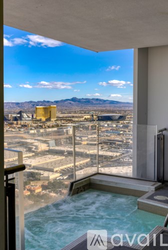 A hot tub is in the foreground of a window looking out at a cityscape.