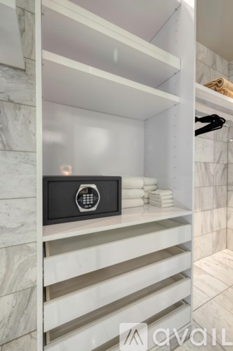 A black and silver safe is on the second shelf from the top in a white cabinet.