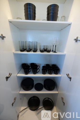 A white shelf with cups and glasses on it.