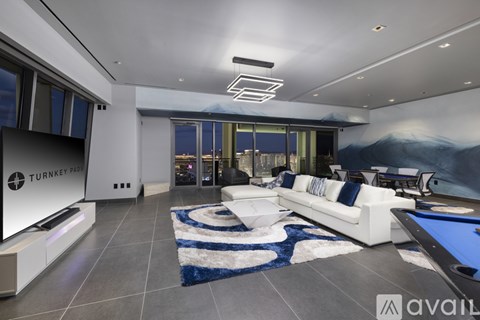 A modern living room with a pool table and a large painting on the wall.