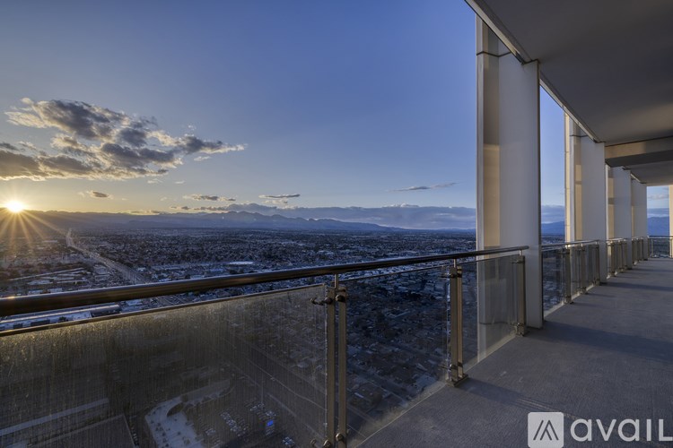 A balcony overlooks a cityscape with the sun setting in the distance.
