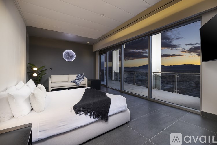 A bedroom with a large bed and a view of the ocean through the glass doors.