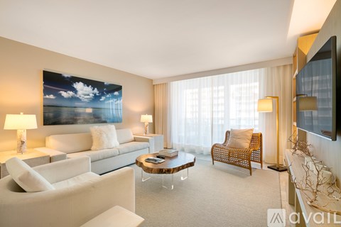 A living room with a large painting on the wall and a white sofa.