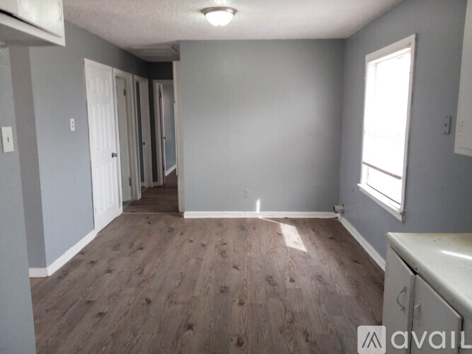 A room with wooden flooring and a window on the right side.