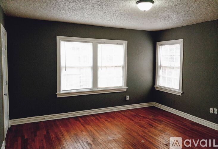 A room with two windows and wooden floors.