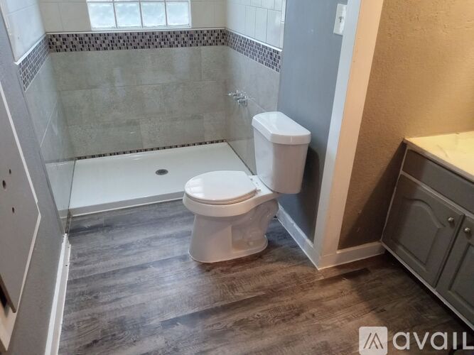 A white toilet sits in a bathroom with a grey floor and a glass shower.