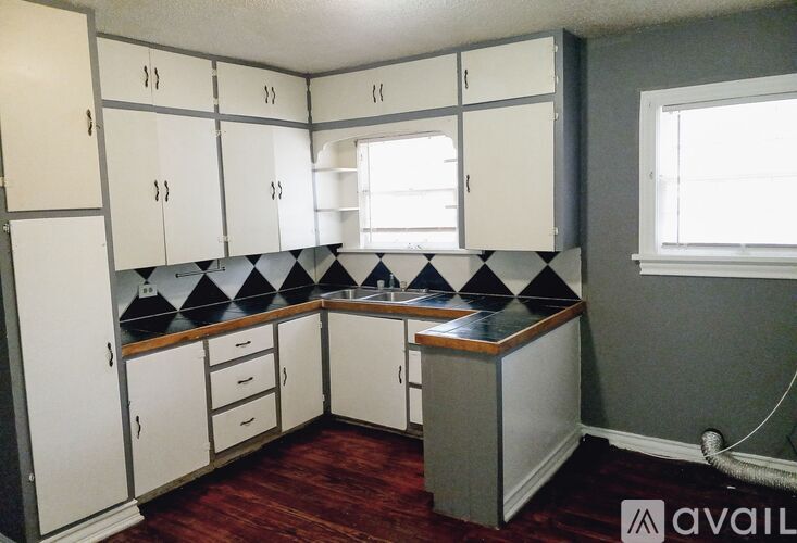 A kitchen with white cabinets and a black and white checkered backsplash.