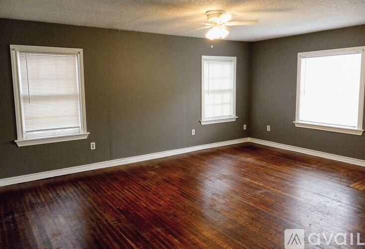 A room with wood flooring and two windows.