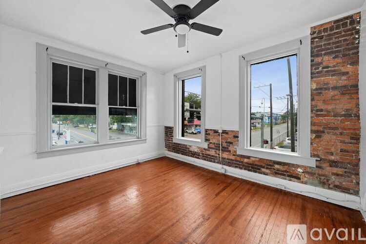 A room with a ceiling fan and two windows.