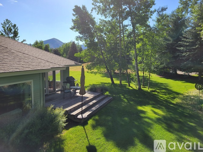 A house with a deck and a mountain in the background.