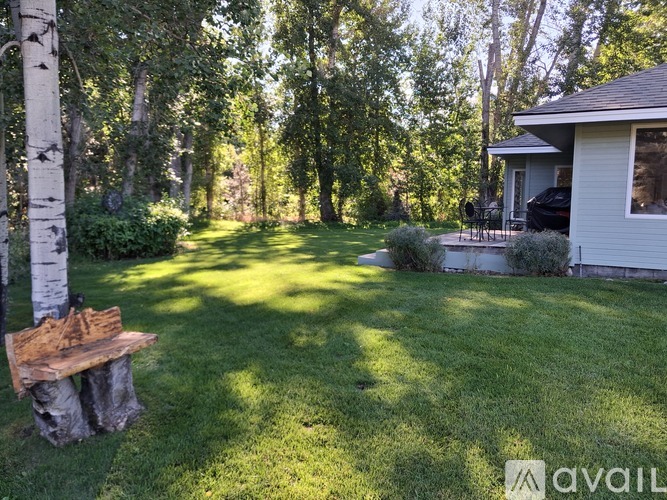 A backyard with a wooden bench and a house.