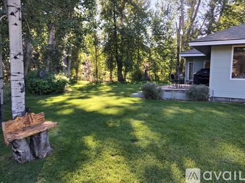 A backyard with a wooden bench and a house.