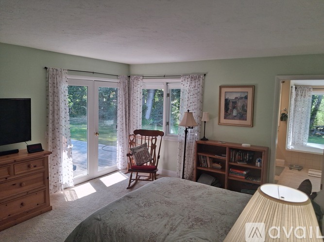 A bedroom with a bed, dresser, chair, and window.