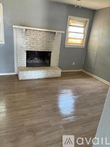 A kitchen with wooden flooring and white cabinets.