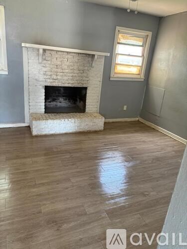 A kitchen with wooden flooring and white cabinets.