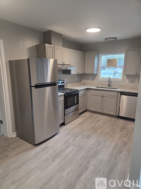 A kitchen with a stainless steel refrigerator and wooden flooring.
