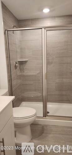 A bathroom with a toilet, a shower with a glass door, and a white countertop.