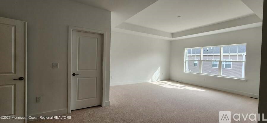 A white room with a large window and a carpeted floor.