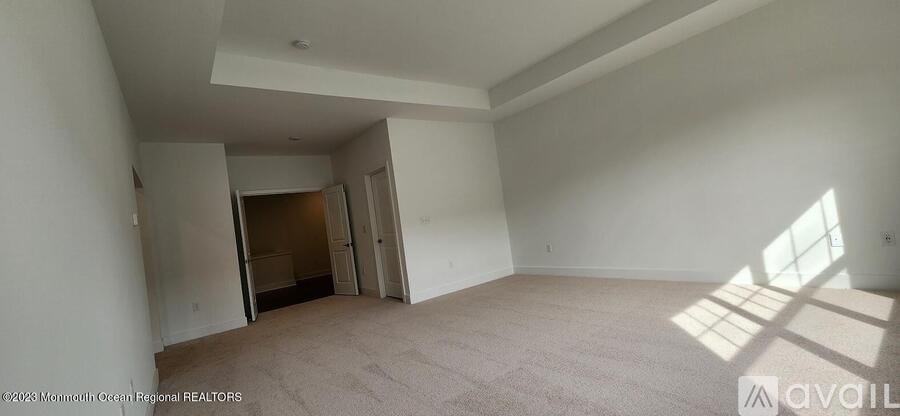 A spacious empty room with a doorway leading to another room.