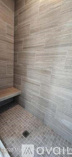 A bathroom with a tiled floor and a wall covered in tiles.