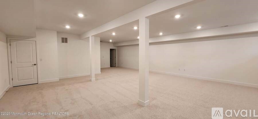 A spacious room with white walls and carpeted floor.