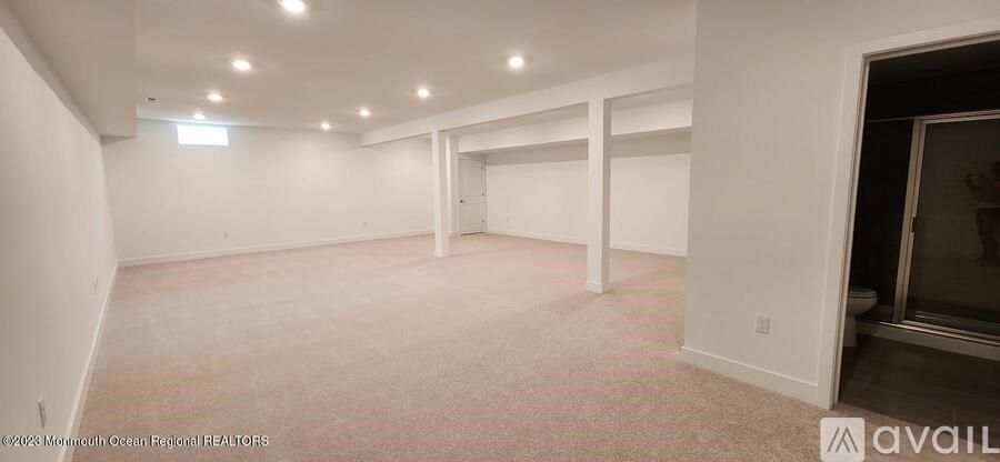 A spacious room with white walls and carpeted floor.