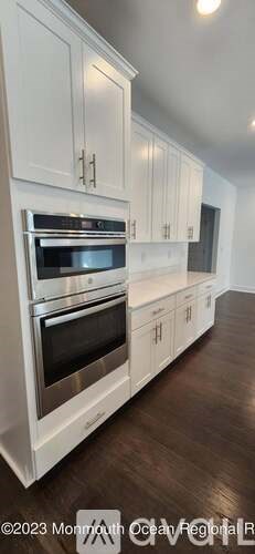 A kitchen with white cabinets and a stainless steel oven.