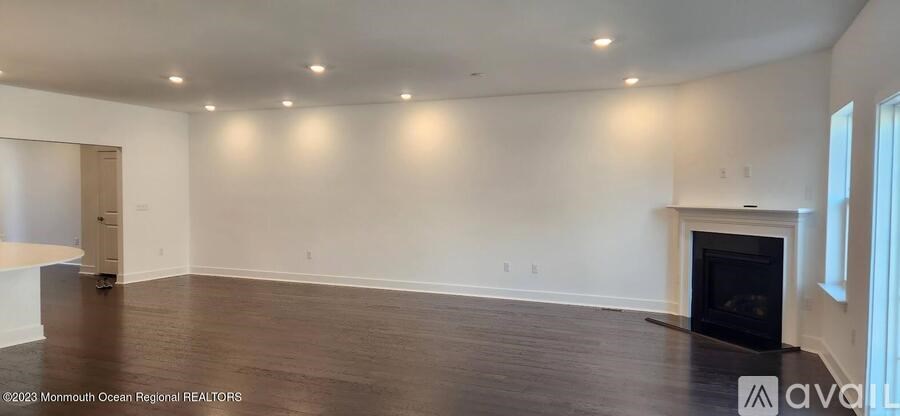 A large, empty room with a fireplace and wooden floors.
