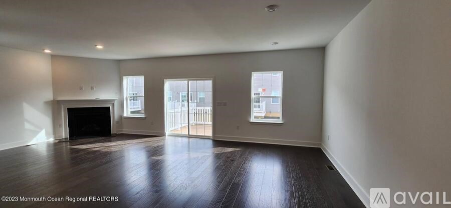 A large, empty room with wood flooring and a fireplace.