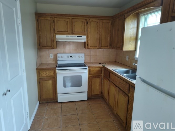 A kitchen with wooden cabinets and a white stove top oven.