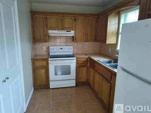 A kitchen with wooden cabinets and a white stove top oven.