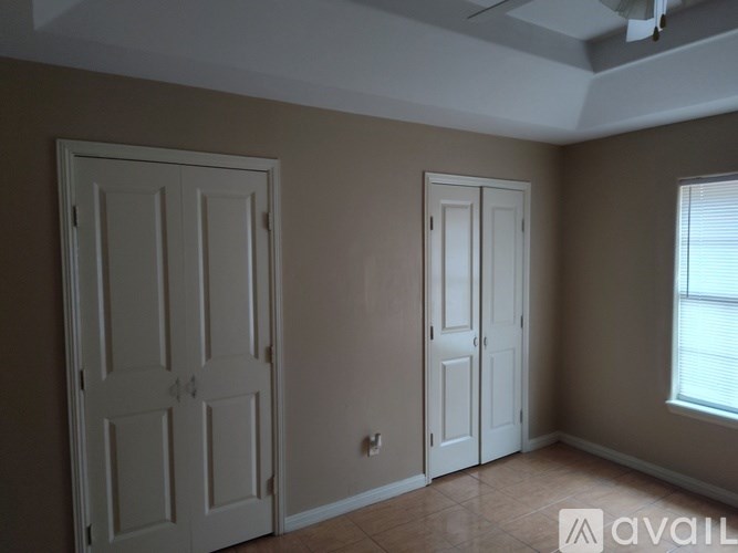 Two white doors in a room with beige walls.