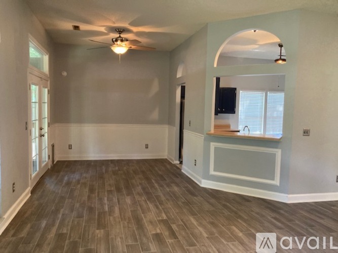 A spacious room with a ceiling fan and wooden flooring.