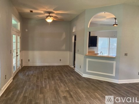 A spacious room with a ceiling fan and wooden flooring.