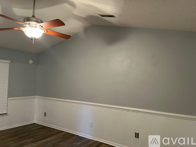 A room with a ceiling fan and wooden flooring.