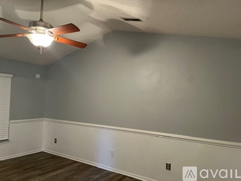A room with a ceiling fan and wooden flooring.