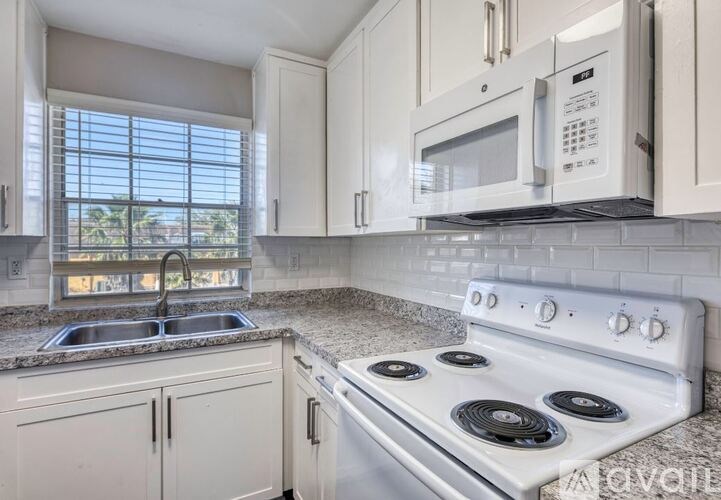 A white stove and microwave in a kitchen with white cabinets.