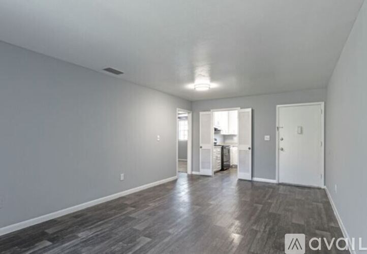 A spacious room with wood flooring and white walls.