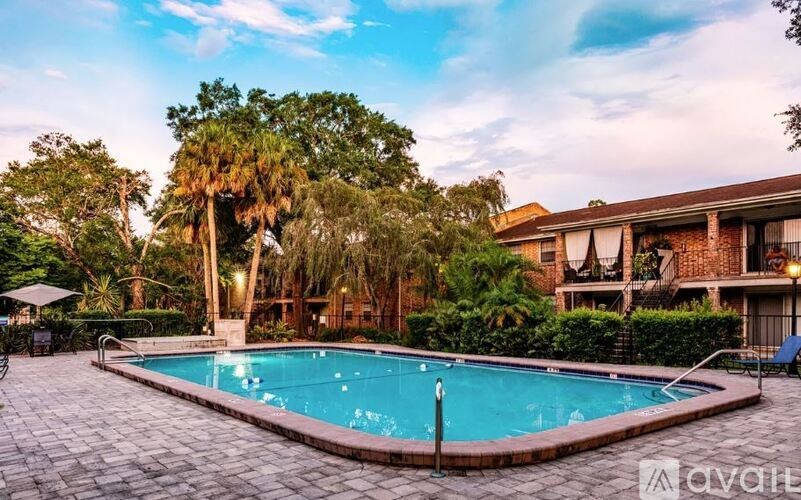 A swimming pool surrounded by a brick patio and palm trees.