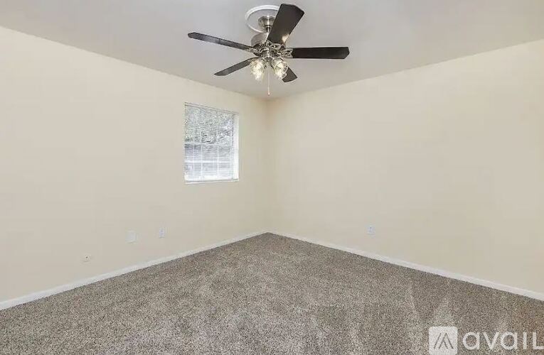 A room with a ceiling fan and carpeted floor.