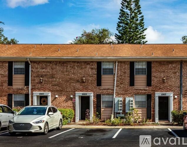 A white car is parked in front of a brick building with the number 1065 on the door.