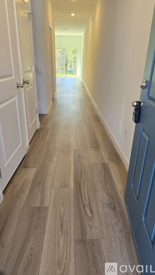 A long hallway with wood flooring and white walls.