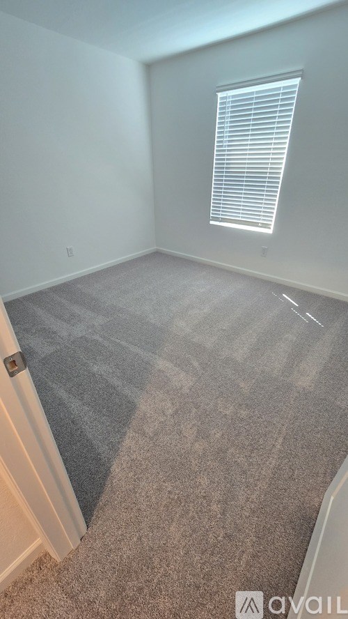 A room with a carpeted floor and a window with blinds.